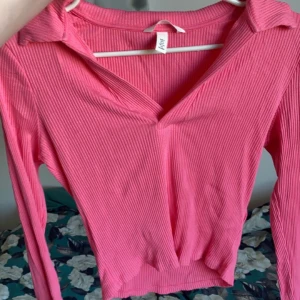 Rosa ribbad topp - Säljer denna rosa topp då jag känner att jag inte kommer få någon användning av den! Den är ribbad och den är v-ringad med en slags krage. Den är köpt på H&M förra våren men har använt den 1-2 gånger så den är i nyskick kan man säga.💓