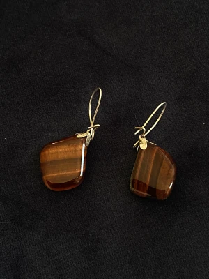 Örhängen tigeröga  - Små fina örhängen med kristaller.   Tigeröga främjar energi, framåtanda och gör det lättare att tro på dina egna förmågor. En mycket värmande och upplyftande sten som löser upp blockeringar i energifältet.