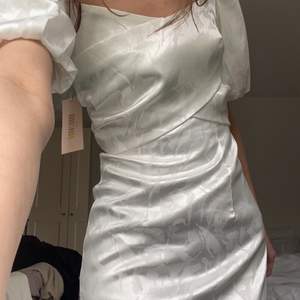 Säljer denna snygga vita klänning i satin med puffärmar. Helt ny med prislappar kvar! Passar perfekt till studenten till exempel.