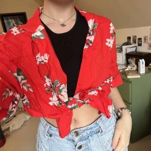 Röd blommig skjorta - Röd blommig skjorta som är perfekt som är perfekt att knyta, som en bikini cover up, eller bara knäppt över ett par jeans🤩 I oanvänt skick men behövs strykas. På mig som är en S sitter den oversiced.💖