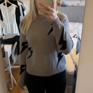 Grå stickad tröja - Grå tröja med svarta blixtar från Shein. Står ingen storlek i tröjan men skulle säga att den passar XS/S/M. Använd fåtal gånger, så i bra skick. Skicka privat vid frågor <3