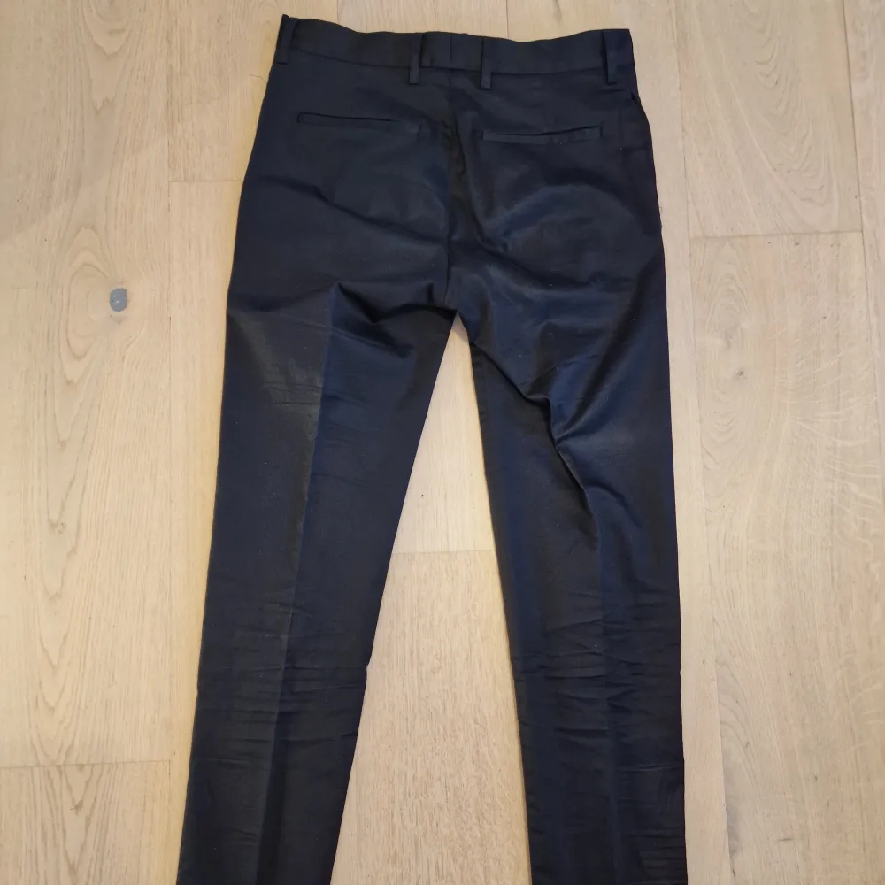 Ett par svarta och lätt blanka byxor från Filippa K med diskreta pressveck.  Storlek 44. Slim passform  Knappt använda.. Jeans & Byxor.