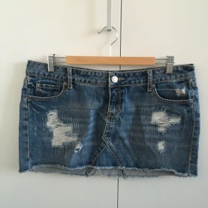 Jeanskjol från Amisu - Min systers jeanskjol från Amisu, begagnad men i mkt gott skick! Med slitagedetaljer. Mått: midja 45,5 cm, längd fram 28 cm och bak 31 cm. Lapp saknas men gissar på M eller möjligen L.