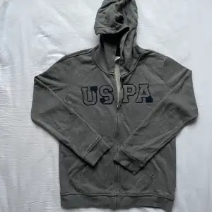 Grå USPA zip up tröja i bra skick finns inga tydliga tecken på användning. Storlek M/S