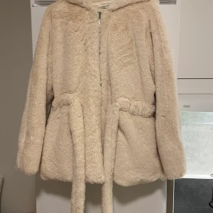 Ny pälsjacka  - Oanvänd pälsjacka. Köpt för 620kr i Asos. Färgen är créme eller ljusbeige. Storlek XS men passar också S. Ganska stor huva. Skickar med frimärken (39kr) eller spårbart. Priset kan diskuteras 