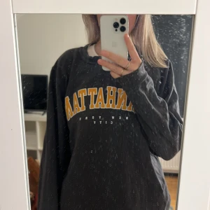 Mörkgrå sweatshirt - Mörkgrå sweatshirt med orange text ”Manhattan”. Sjukt gosig tröja, strl S!