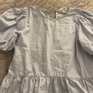 Blå blus - En babyblå mycket söt blus med puffärmar och en volang längst ner.  