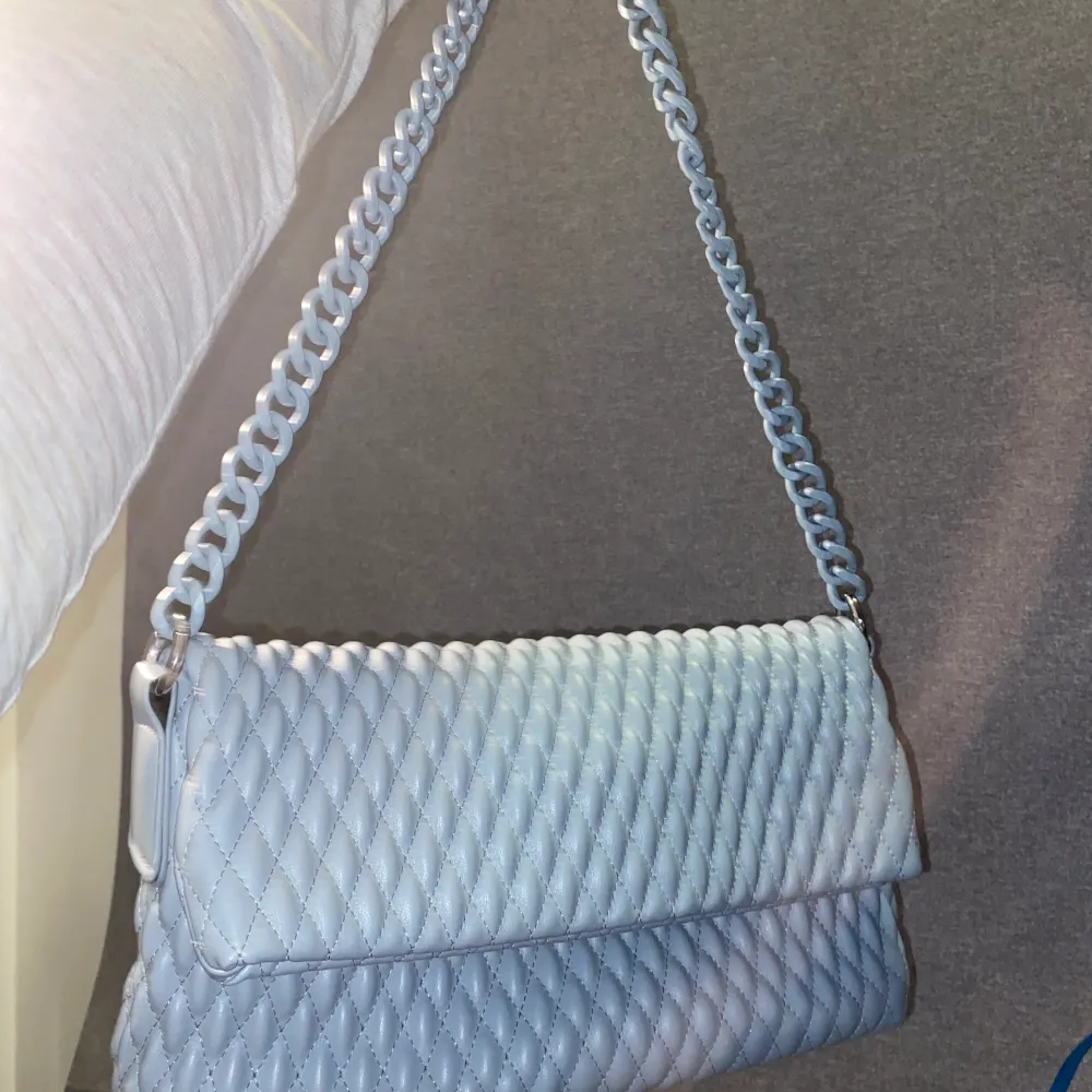 En blå axelväska med mönster. . Väskor.