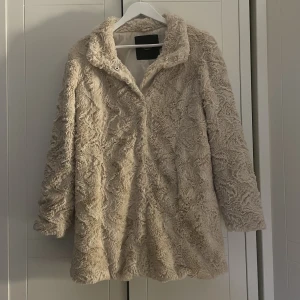 Vit jacka/kappa vero moda  - Vit fluffig jacka/kort kappa från vero moda, strl L. Knappt använd. Har en reva på insidan i fodret som säkert går att laga lätt för den händige, men det är inget som syns utvändigt eller påverkar funktionen.