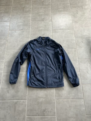 Nike jacka  - En Nike jacka som aldrig är använd och som nu tyvärr blivit liten. Jackan är som i nyskick.