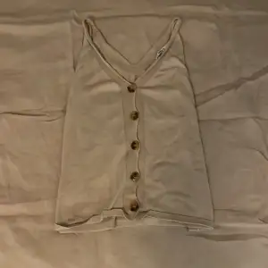 En fin och beige tröja/linne, som har 5 bruna knappar på framsidan, storlek XS