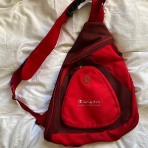 En röd slingbag/onestrap/väska från champion. Ganska rymlig och i fint skick!