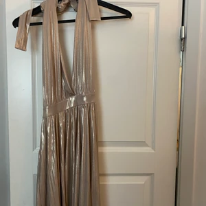 Balklänning  - Guldig ”balklänning” från nelly. Använd 1 gång. Öppen i ryggen och knytning runt halsen. Jätte bra skick 💕