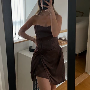 Festklänning i siden - Oanvänd och eftertraktad festklänning i brunt sideninspirerande tyg🤎 prislapp sitter kvar! Det är storlek M men mer som en S. 