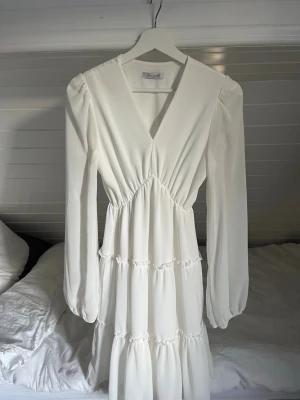 Studentklänning - Säljer denna jättefina vita klänningen perfekt till studenten! Köpt från DesignBySi. Endast använd 3 gånger och i superfint skick! 