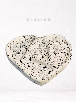 Hjärtfat i lera med svart stänkmönster - Unikt hjärtformat fat i vit lera med svart stänkmönster. Perfekt som smyckesfat eller dekoration. Fatet har en modern och konstnärlig känsla och passar snyggt på skrivbordet eller nattduksbordet.