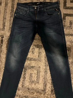Mörkblå jeans från Replay - Snygga mörkblå skinny jeans från Replay med klassisk femficksdesign och diskreta slitningar framtill. Jeansen har en smal passform och är tillverkade i stretchigt denimtyg för extra komfort. Perfekta för en trendig och avslappnad look. Helt nya klippte av taggarna innan jag prova dom och de passa tyvärr inte så aldrig använda.