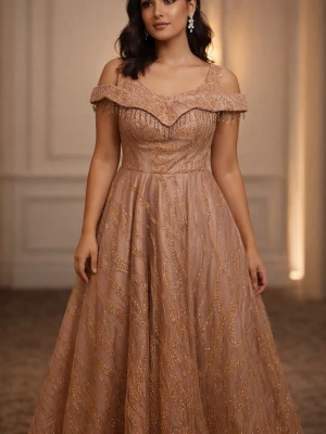 Champagnefärgad offshoulder klänning - Säljer en elegant champagnefärgad långklänning med offshoulder och glittrigt mönster i guld. Klänningen har vacker volangdetalj vid axlarna och snörning i ryggen. Perfekt för bal eller speciella tillfällen.