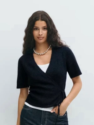 Mörkblå omlottkofta - Säljer en svart omlottkofta från Monki med korta ärmar och knytband i sidan. Koftan har en djup v-ringning och är gjord i ett mjukt, fluffigt material som känns riktigt skönt. Perfekt att styla över ett linne eller t-shirt. Ny pris 360. Pris kan diskuteras. Använd fåtal gånger.