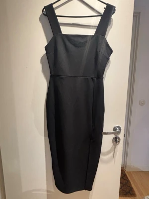 NY! Svart klänning  - Oanvänd! Figursydd svart midiklänning med slits. 