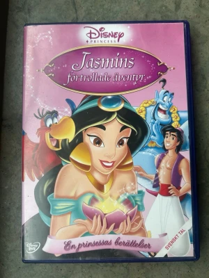 Jasmines förtrollade äventyr dvd - DVD-film med Disney Princess: Jasmins förtrollade äventyr. Filmen har svenskt tal och text på svenska, danska, norska, engelska, isländska, estniska och lettiska. Ljudformatet är Dolby Digital 2.0. Speltid 64 minuter. Produktionsår 2005. Innehåller även extramaterial som Jasmins juvel-spel och musikvideo.  Finns på språk: Svenska, Finska, Danska, Norska, Engelska   OBS!! skivorna är begagnade så det kan förekomma repor/hairlines på skivorna, men då jag kollar igenom alla filmer jag säljer 