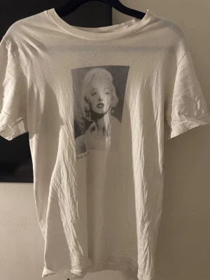  t-shirt - Vit t-shirt från Celini med ett svartvitt grafiskt tryck på framsidan. Klassisk rund hals och korta ärmar. Materialet känns mjukt och lätt, perfekt för dig som gillar stilrena plagg med en twist. Storlek S