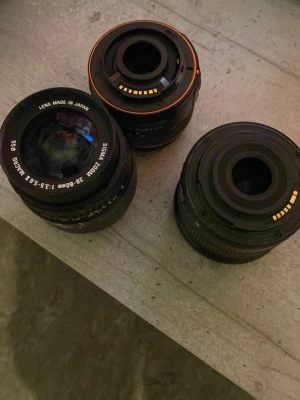 Sigma 28-80mm f/3.5-5.6 Macro + 2 extra objektiv - Paket med Sigma 28-80mm f/3.5-5.6 Macro-objektiv och två extra objektiv. Passar systemkameror, autofokus och asfärisk lins. Alla objektiv ser ut att vara i gott skick utan synliga repor eller skador. Perfekt för både nybörjare och entusiaster.