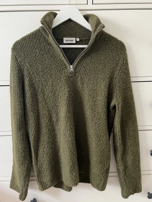 Stickad tröja från Weekday - Olivgrön stickad tröja från Weekday med halv dragkedja och hög krage. Tröjan har en grovstickad struktur och långa ärmar. Tröjan är något nopprig. 