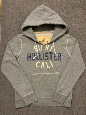 Vintage Hollister Hoodie - Extremt sällsynt och unik Hollister Hoodie med tryck | Hoodien har en unik sliten & distressed design! | Mycket bra skick, (lite smutsig vid högrs ärmen men syns knappast alls, se sista bild)| Storlek S | Längd≈ 65 cm, Bredd 55 cm under armhål-armhåla| Modell 175cm, 68kg | Priset ej hugget i sten! 