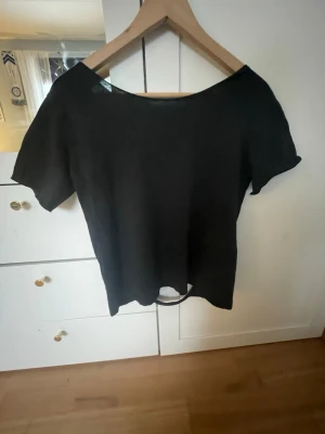Svart topp med öppen rygg - Cool svart topp med korta ärmar och unik öppen rygg med snörningsdetaljer. Tröjan kommer från början från lager157 och är i storlek 160 (passar xs) men jag har gjort om den så att det är öppen rygg! 