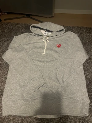 Grå hoodie från Comme des Garçons Play - Snygg grå hoodie från Comme des Garçons Play. Skön fit, storlek lx sitter som en L. 