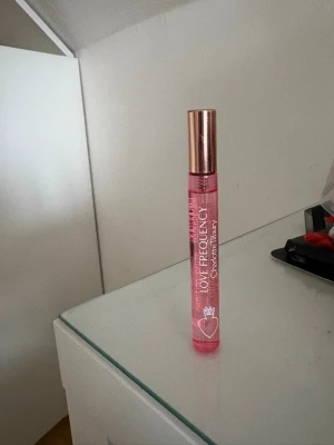 Love Frequency parfym från Charlotte Tilbury - Love Frequency parfym från Charlotte Tilbury i en smidig rosa glasflaska med roséguldfärgat lock. Flaskan har ett hjärtmotiv och text i vitt. Perfekt storlek att ha med i väskan och doften är feminin och modern. Detta är resestorleken 10ml. Inte ens testad. Den kom i ett set men jag har valt att behålla lipglossen i setet har doftat parfymen i butik det var inget för mig. Man kan få med kartongen om man vill. Nypris 279kr