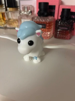 Adopt me - En liten vit plastfigur föreställande en pegasus med stora svarta ögon, blå man och svans samt rosa detaljer på öronen. Vingarna är utsträckta och den har en liten blå stjärna på ena benet. Perfekt som dekoration eller leksak.