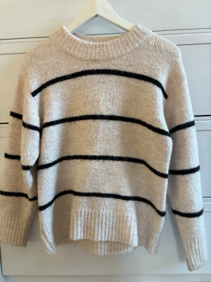 Beige randig stickad tröja - Jättefin randig stickad tröja. Sticks inte så mycket. Rensar garderoben. Köp helst med PostNord. Nästan aldrig använd