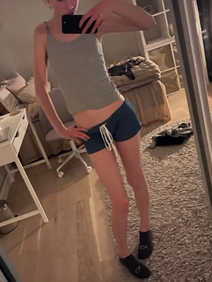 Blåa shorts med snörning - Snygga blåa shorts med vit snörning i midjan. Modellen är lågmidjad och har en sportig look, perfekta för sommarens varma dagar. Tillverkade i ett mjukt och bekvämt material som passar till avslappnade outfits.