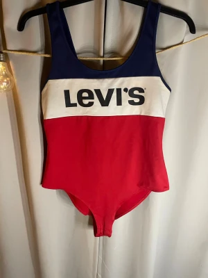 Levi's färgblockad body - Snygg body från Levi's med breda axelband och färgblock i marinblått, vitt och rött. Stor logga framtill. Klassisk, sportig modell i stretchigt material som passar perfekt för vardaglig klädseln .