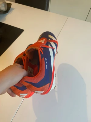 Adidas Predator blå/röd fotbollsskor - Säljer ett par Adidas Predator fotbollsskor i blått och rött med vita detaljer.Dom är lite skadade syns inte eller påverkar inte spelet på något sätt.