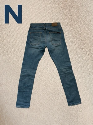 Nudie jeans lean dean - Authentic Nudie Jeans Lean Dean model in light wash denim, size 28/30, purchased in Gothenburg. These jeans offer a slim fit, showing some wear with fading and subtle distressing adding to their unique character. Please refer to photos for specific details, as these are pre-owned. Feel free to ask any questions!