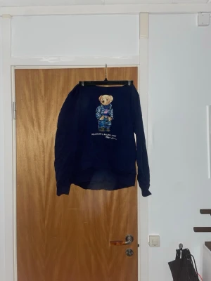 Marinblå hoodie Polo Ralph Lauren - Mörkblå hoodie från Polo Ralph Lauren med den ikoniska björnen på bröstet! Perfekt inför våren/sommaren! Inga defekter! Hör av dig för fler bilder!