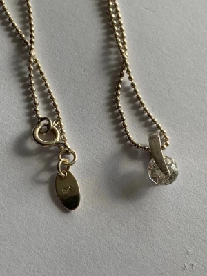 Silverhalsband med hänge - Snyggt halsband i äkta silver (925) med kulkedja och ett glittrande, rundslipat hänge i klar sten. Kedjan har en enkel karbinhake och en liten bricka med silverstämpel. Perfekt för dig som gillar stilrena och eleganta smycken.