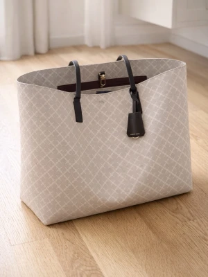 Beige shoppingväska By Malene Birger - Stilren shoppingväska från By Malene Birger i beige med diskret mönster och svarta handtag. Väskan har guldfärgade detaljer och en praktisk innerficka med dragkedja. Perfekt för dig som vill ha en rymlig och trendig väska till vardagen.