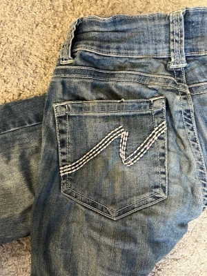 Bootcut Jeans från Nelly - Säljer ett par klassiska blå bootcut jeans från Nelly. Jeans med vit kontrastsöm på bakfickan. (Jenssen ser lite ”kantiga” ut eftersom dem precis torkat efter tvätt)