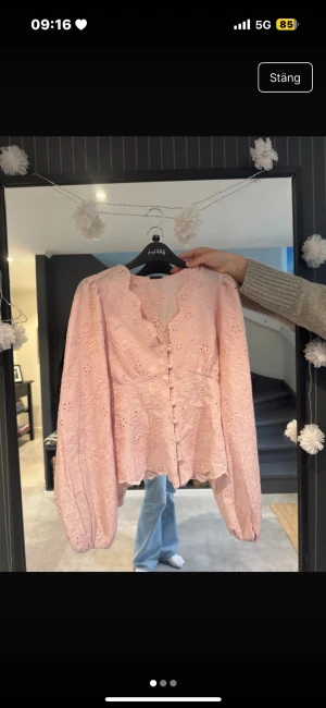 Rosa broderad blus från Gina Tricot - Söt slutsåld ljusrosa blus från Gina Tricot med broderade blommor, klädda knappar framtill och v-ringad hals. Blusen har puffiga långärmar. Helt ny med prislappen kvar. 