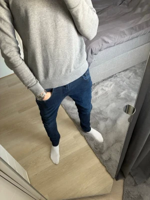 Mörkblå slim fit jeans - Säljer ett par mörkblå slim fit jeans med klassisk femficksdesign och normal midja. Jeansen har smal passform hela vägen ner och är tillverkade i ett stretchigt denimtyg för extra komfort. Perfekta för en avslappnad och snygg stil.