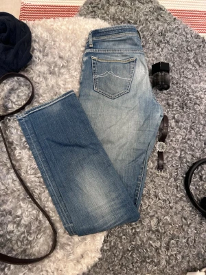 Laidback Jacob Cohën 688 comfort - Säljer ett par blå jeans med raka ben och snygga slitningar. Jeansen har klassisk femficksdesign och kontrastsömmar på bakfickorna. Materialet är denim i bomull och de har en ljus tvätt med markerade partier framtill och baktill.