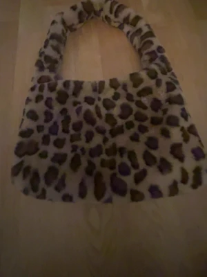 Leopardmönstrad fluffig handväska - Supercool handväska med leopardmönster i beige och brunt. Väskan är gjord i ett mjukt, fluffigt material och har en bred axelrem. Perfekt för dig som vill sticka ut med en trendig accessoar. Har aldrig använt den och har ändå hyfsat mycket plats. Och två olika fack.