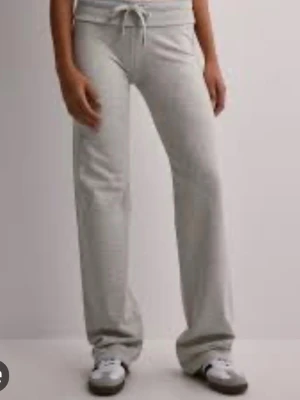 Grå mjukisbyxor med dragsko - Snygga grå mjukisbyxor med raka ben och dragsko i midjan. Tillverkade i mjukt och bekvämt material, perfekta för en avslappnad stil. Byxorna har resår i midjan och en enkel, stilren design.