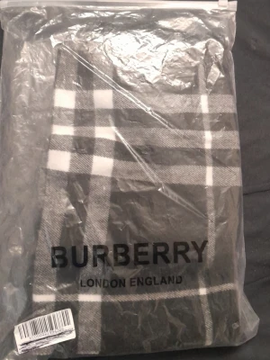 Svartvit rutig halsduk  - Stilren halsduk  i svart och vitt med klassiskt rutmönster. Tillverkad i mjukt material som känns skönt mot huden. Perfekt accessoar för att lyfta din outfit med en tidlös och elegant touch.