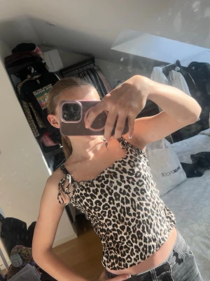 Leopardmönstrad linnetopp med knyt - Säljer en leopardmönstrad linnetopp med tunna axelband som knyts på axlarna. Toppen har en figurnära passform och är perfekt för dig som vill sticka ut. Materialet känns mjukt och lätt, troligen polyester eller bomull. Supersnygg till både jeans och kjol! Är i storlek M men upplevs mindre! Nästan som en S eller XS.