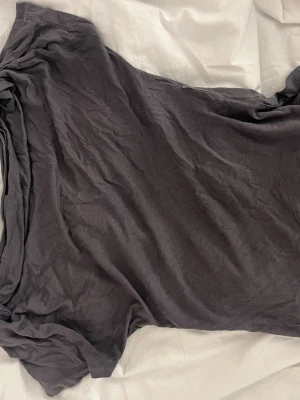 Svart basic t-shirt i bomull - En grå tröja som sitter tajt i midjan och lite lösare vid axlarna 